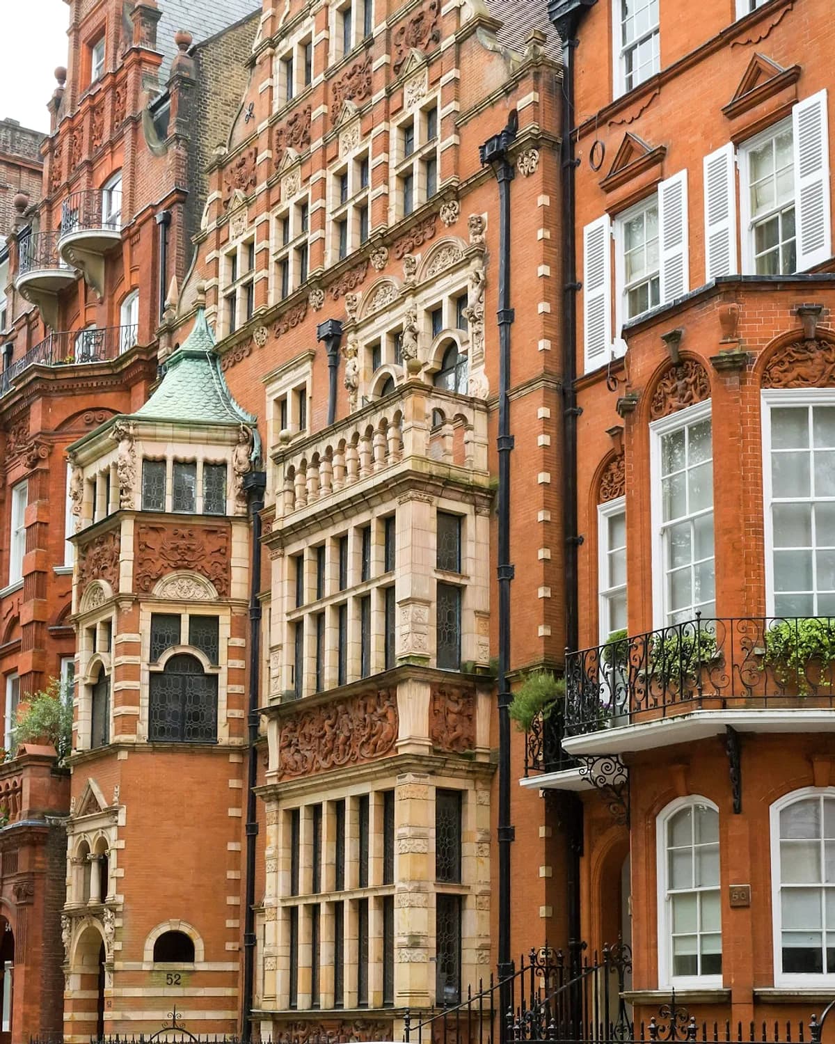 Red-brick Victorian mansion facades in London, with carved stone and iron balconies