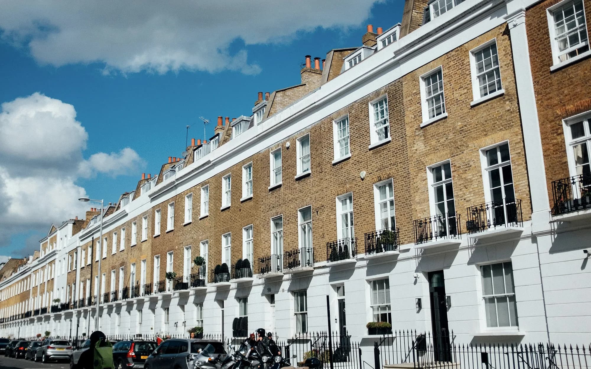 A Georgian terrace in London, brick above and stucco below, under a blue sky